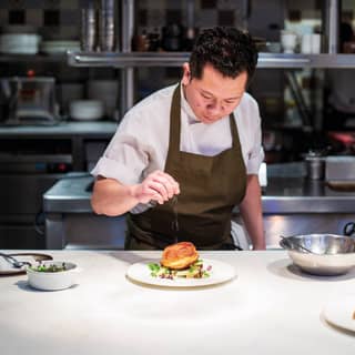 Chef completing a dish to serve by sprinkling seasoning on the top