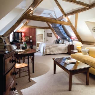 Spacious attic hotel room with wood-beamed ceiling and large yellow sofa
